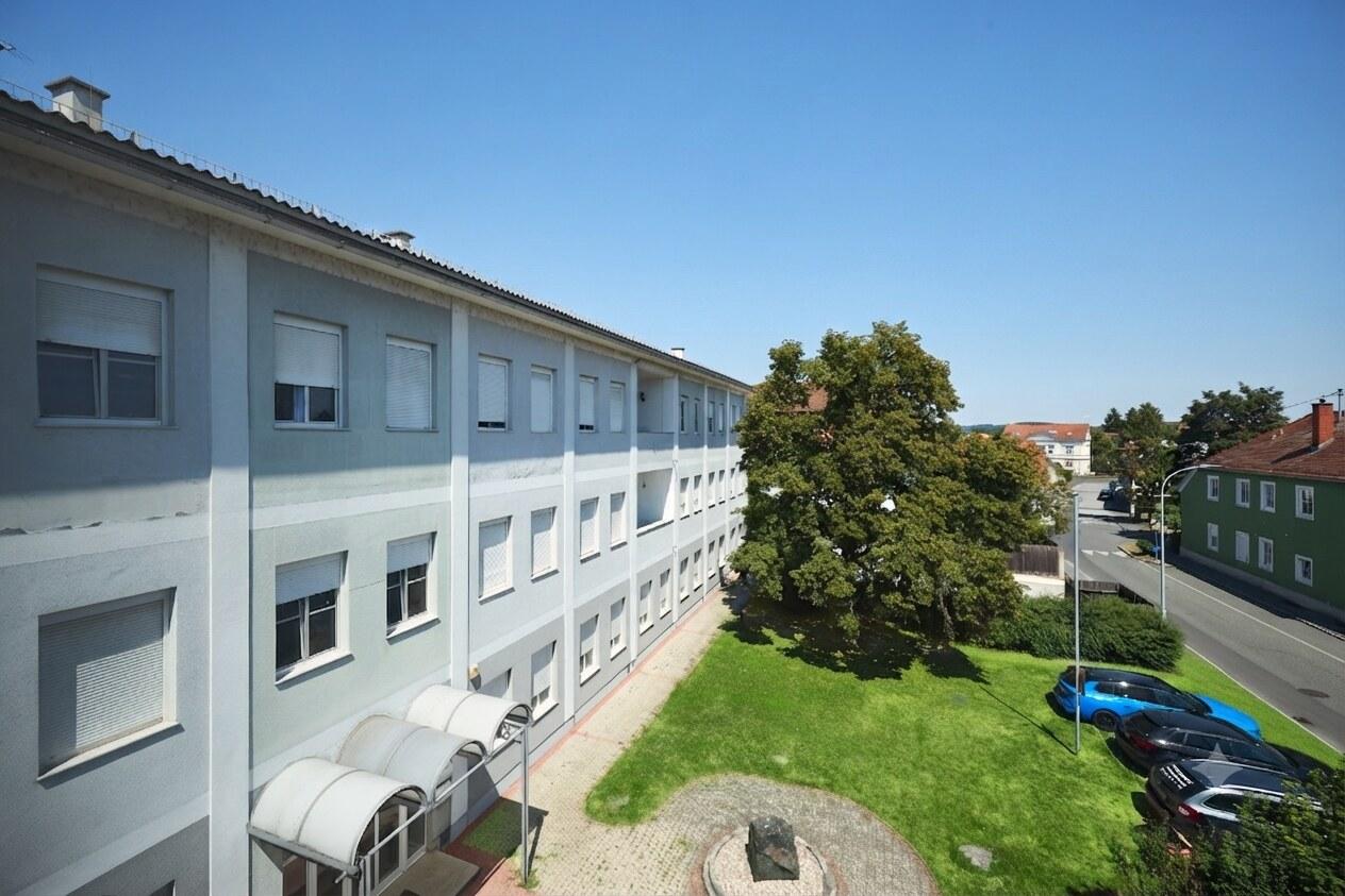Das Wohnhaus Wieskapellenweg 8 von oben entlang der Längsseite, mit begrüntem Innenhof und altem Laubbaum.